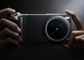 A person holding the Vivo X300 Ultra smartphone horizontally, showcasing its large circular rear camera module with a ZEISS-branded lens in a dark, dramatic lighting setup